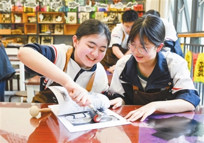 左图为2025年3月27日,重庆巴川量子学校版画社团的两名女生在一起制作版画。 新华社发