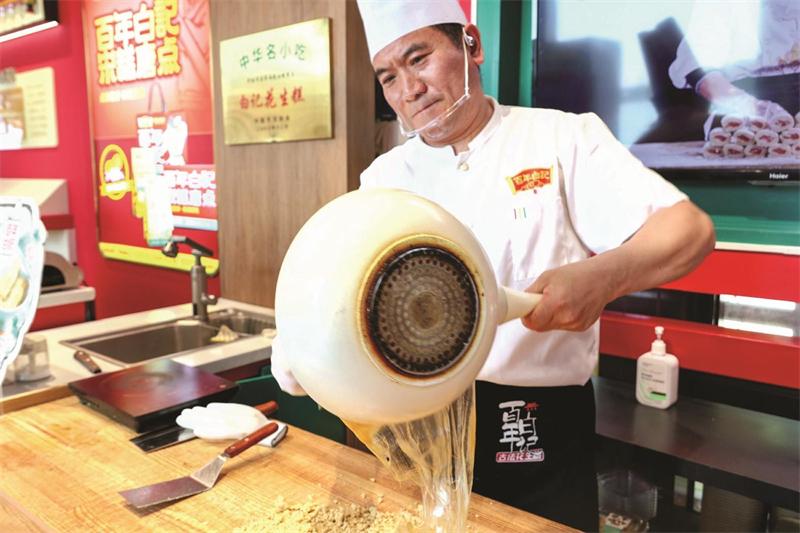 金黄色的糖浆在百年白记非遗传承人手中被拉出&ldquo;千层薄纱&rdquo;。 赵 晨 摄