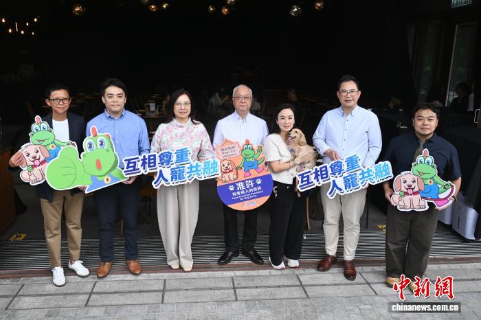7月9日，香港首批食肆正式允许顾客携带犬只入内用餐。图为香港特区政府环境及生态局局长谢展寰(左四)等嘉宾在食肆前合影。　中新社记者 李志华 摄