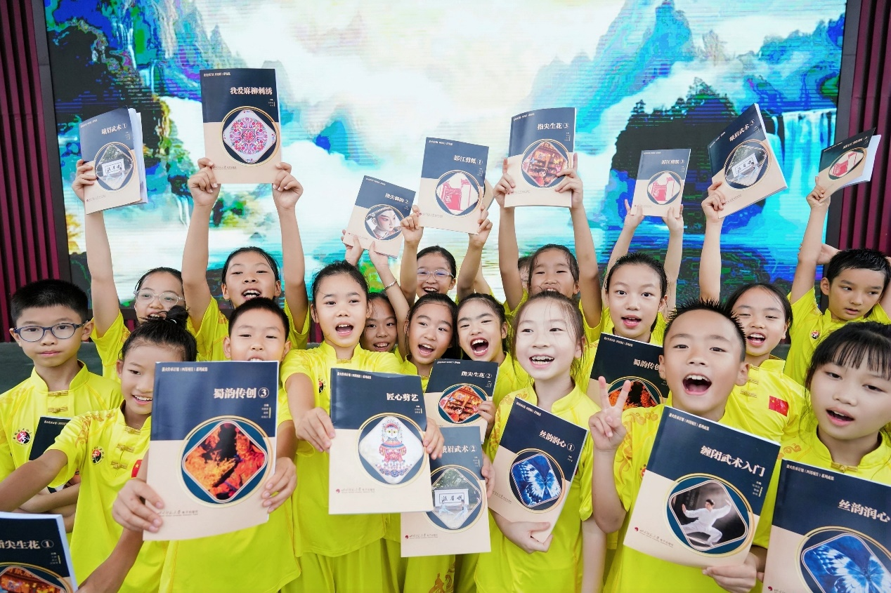 孩子们举着首套《非遗进校园课程建设学本》
